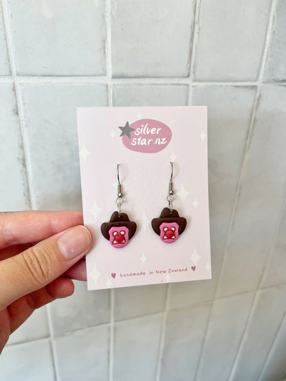 A hand holds a card displaying Bubble 'O Will Polymer Clay Earrings from silverstar.nz, handmade in New Zealand. The card features small stars on a light background.