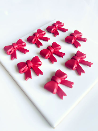 A set of nine Red Bow Polymer Clay Earrings from silverstar.nz, arranged in a 3x3 grid on a white square surface, showcases precision craftsmanship. The uniform red bows beautifully contrast against the clean background.