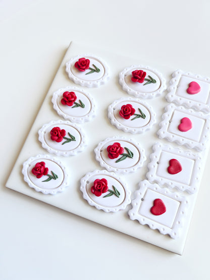 A square board features six oval cookies with red roses and four square cookies with pink hearts, echoing the distinctive design of silverstar.nzs Framed Rose Polymer Clay Earrings. Each cookies decorative edges reflect the craftsmanship of these handmade earrings, arranged neatly in a grid.