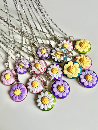 A selection of vibrant Daisy Polymer Clay Necklaces from silverstar.nz is beautifully arranged on a white surface. Each handmade pendant showcases a daisy-like design in an array of colors—purple, yellow, and pink—set against backgrounds of green, pink, and blue. These necklaces are perfect examples of exquisite New Zealand jewelry craftsmanship.